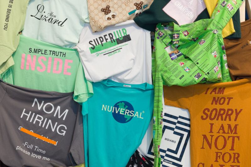 Multicolored t-shirts hanging off of a wall.